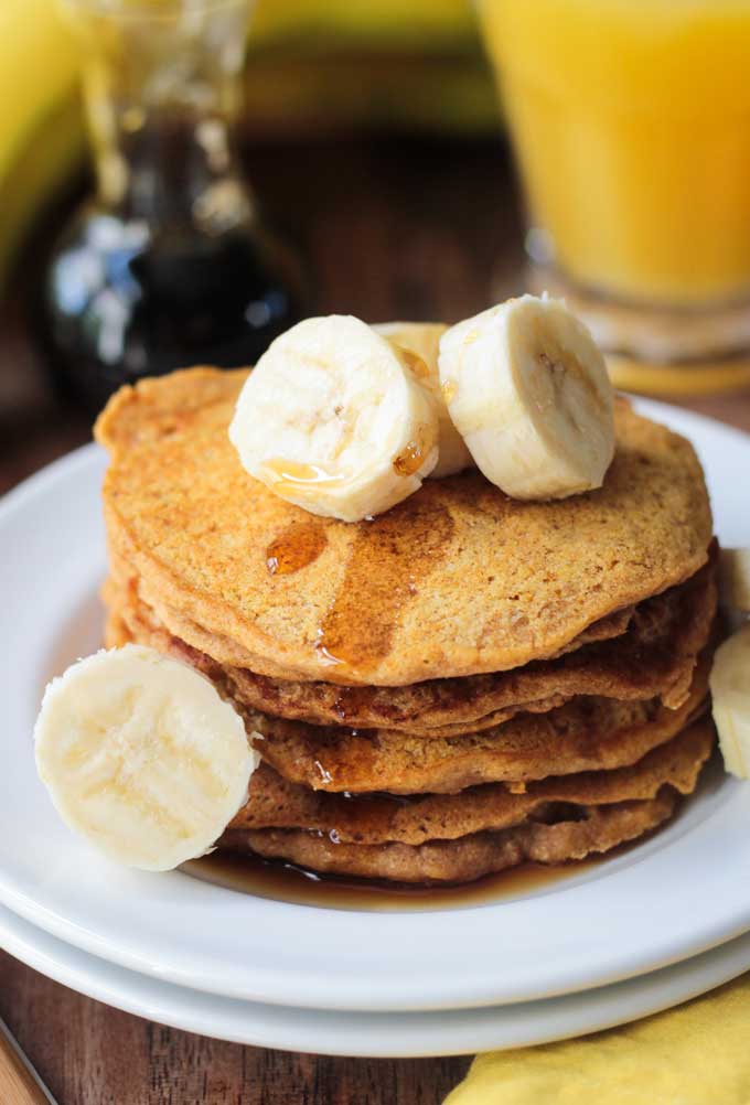 Banana Pumpkin Spice Pancakes topped with sliced bananas and a drizzle of maple syrup.
