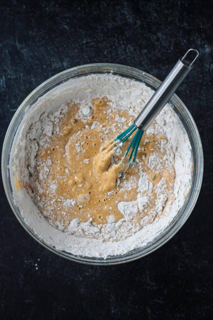Wet and dry ingredients being whisked together in a bowl.