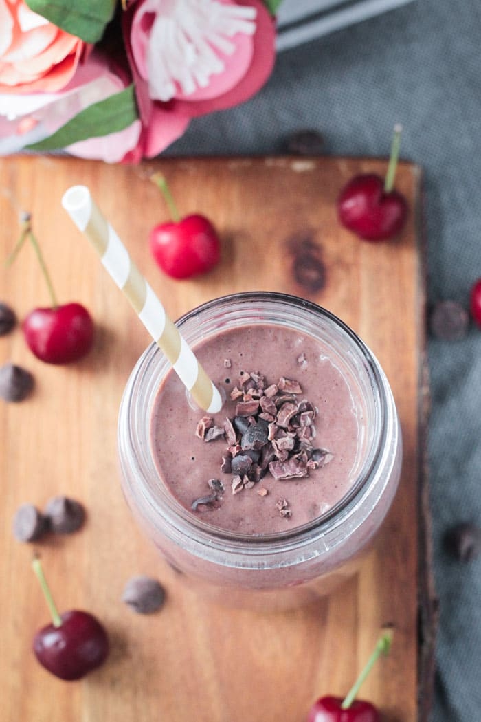 Close up overhead shot of cacao nibs and chocolate chips on top of a creamy drink.