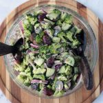 Healthy broccoli salad in a glass serving bowl with salad forks.