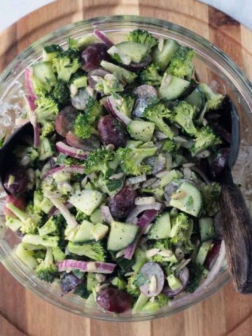 healthy broccoli salad in a glass serving bowl with salad forks