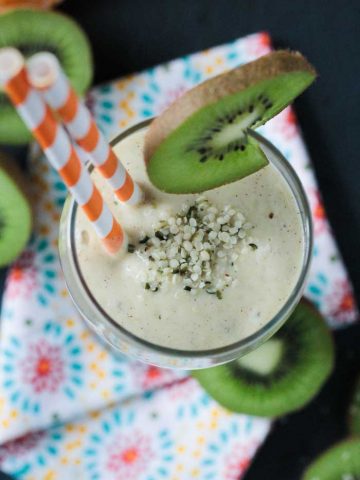 Looking down into a glass of kiwi mango smoothie with hemp hearts sprinkled on top.