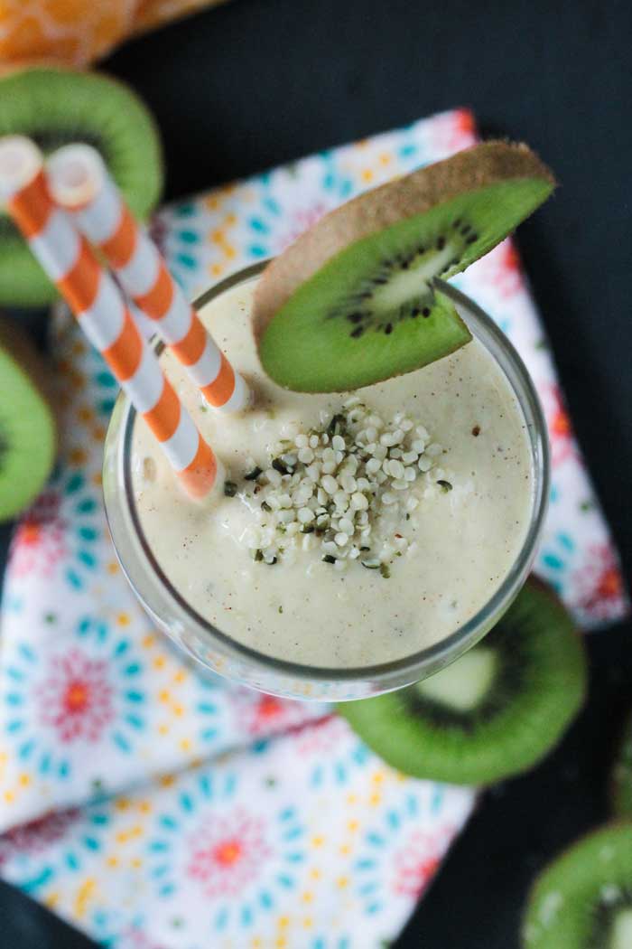 Looking down into a glass of kiwi mango smoothie with hemp hearts sprinkled on top.