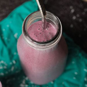 Coconut Berry Smoothie in a glass with a reusable straw.
