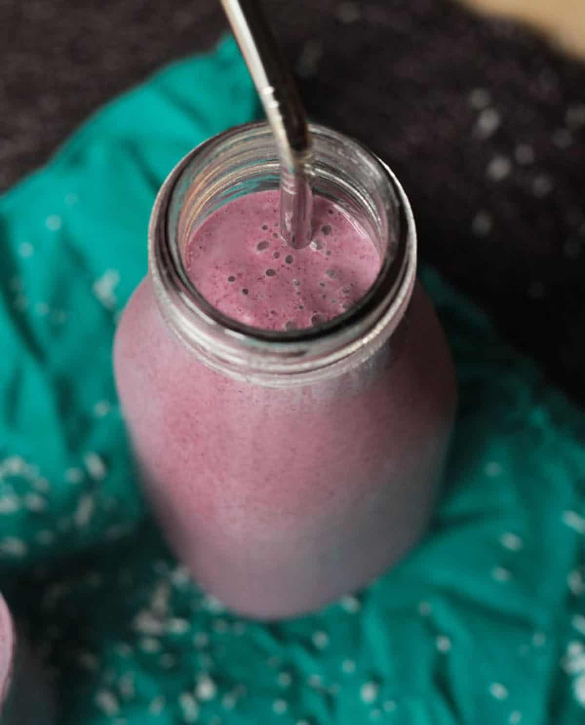 Coconut Berry Smoothie in a glass with a reusable straw.