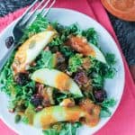 kale salad with apple slices and pumpkin dressing drizzled over the top
