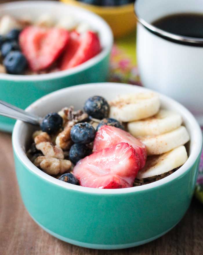 Close up of fresh strawberries and  blueberries in a bowl with a spoon.