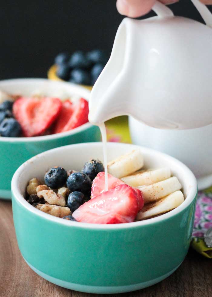 Milk being poured onto fruit, oats, and nuts.