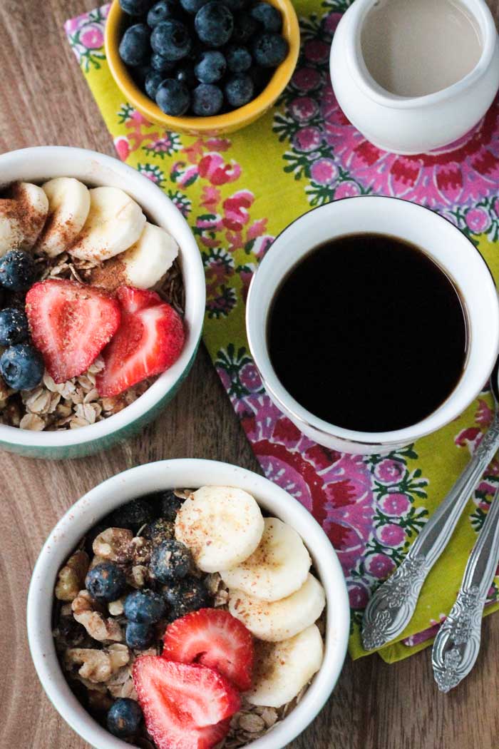 Overhead view of sliced bananas, raw oats, berries, and walnuts.