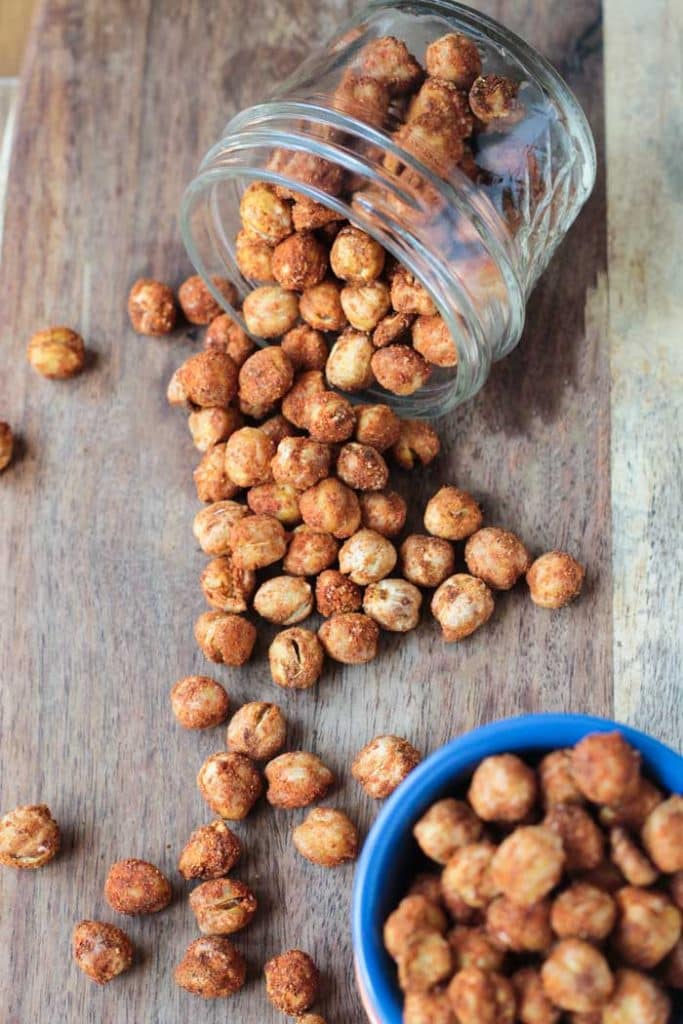 Smoky Roasted Chickpeas spilling out of a glass jar on it's side. 