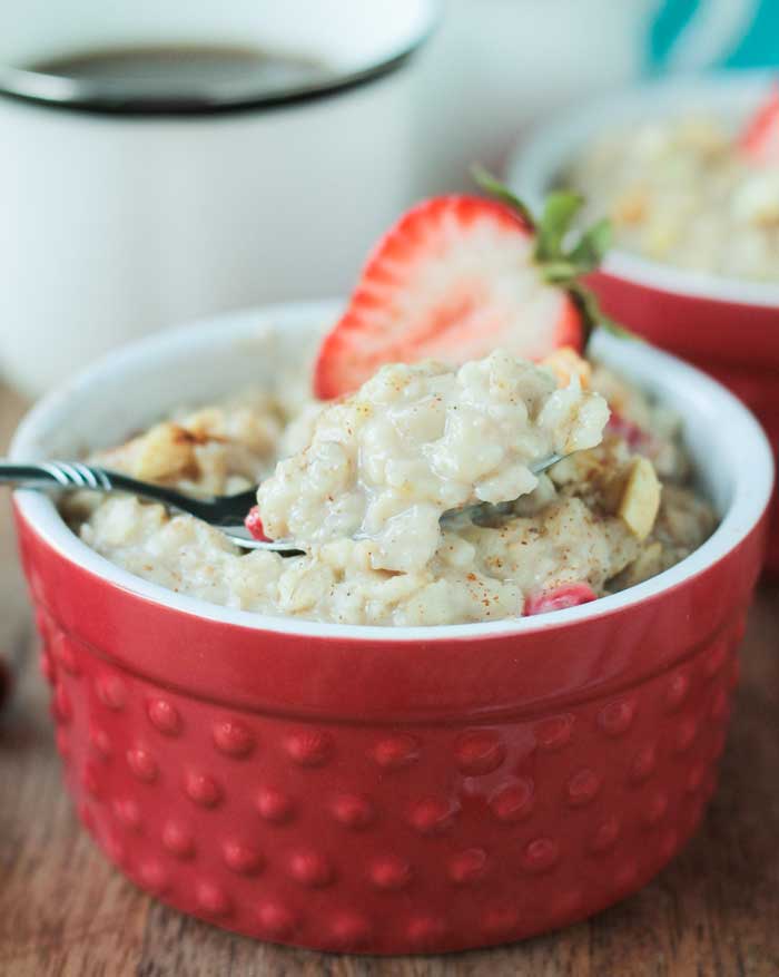 Close up of a spoonful of creamy peanut butter oatmeal in a red bowl
