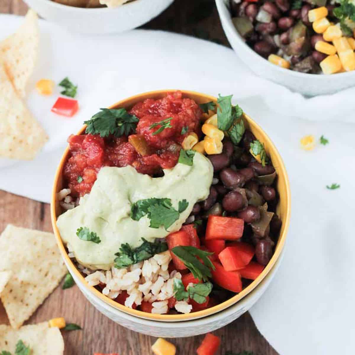 Rice, black beans, peppers, corn, salsa, and avocado sauce in a bowl
