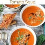 Two bowls of tomato soup next to the soup pot.
