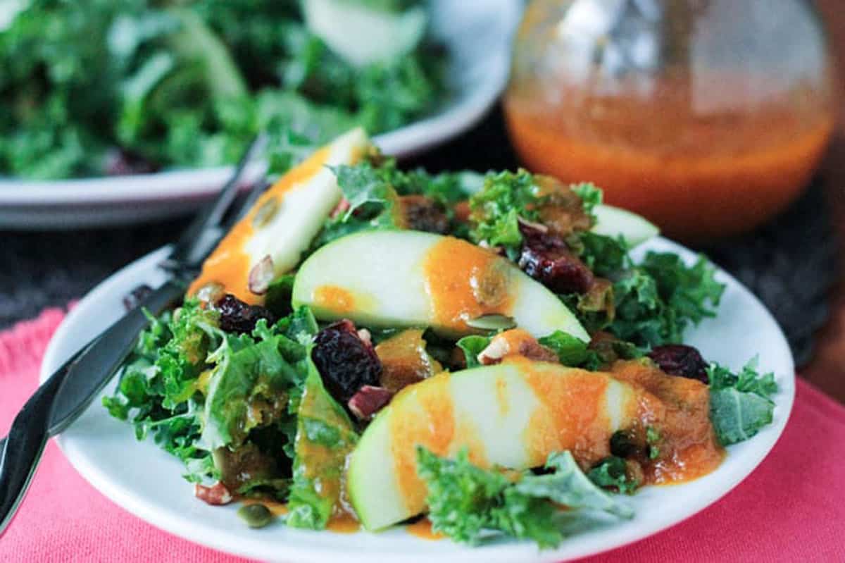 Autumn Kale Apple Salad w/ Warm Pumpkin Vinaigrette - protein packed, sweet and tart, and highly nutritious. The perfect light fall lunch or a starter for a heartier meal. Sliced apples drizzled with warm pumpkin dressing over a kale salad.