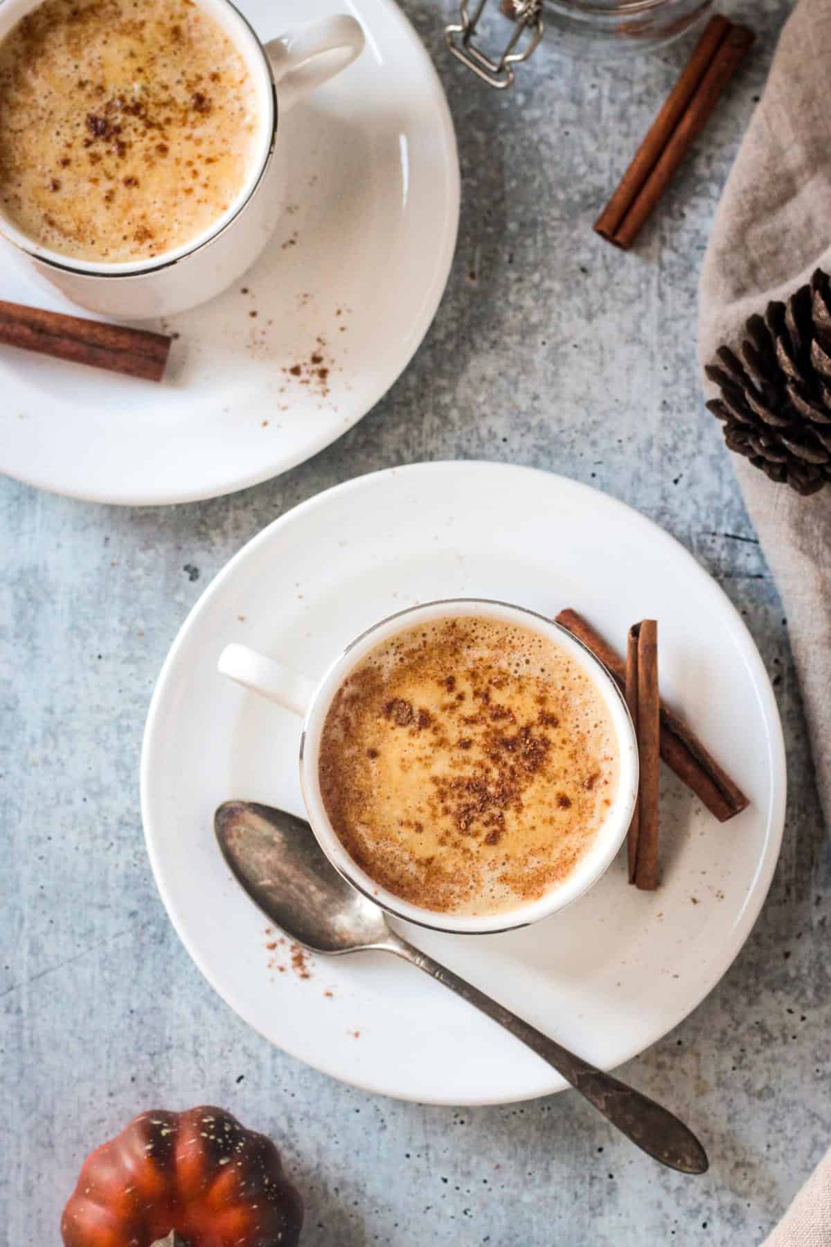 Two cups of pumpkin spice coffee on saucers.