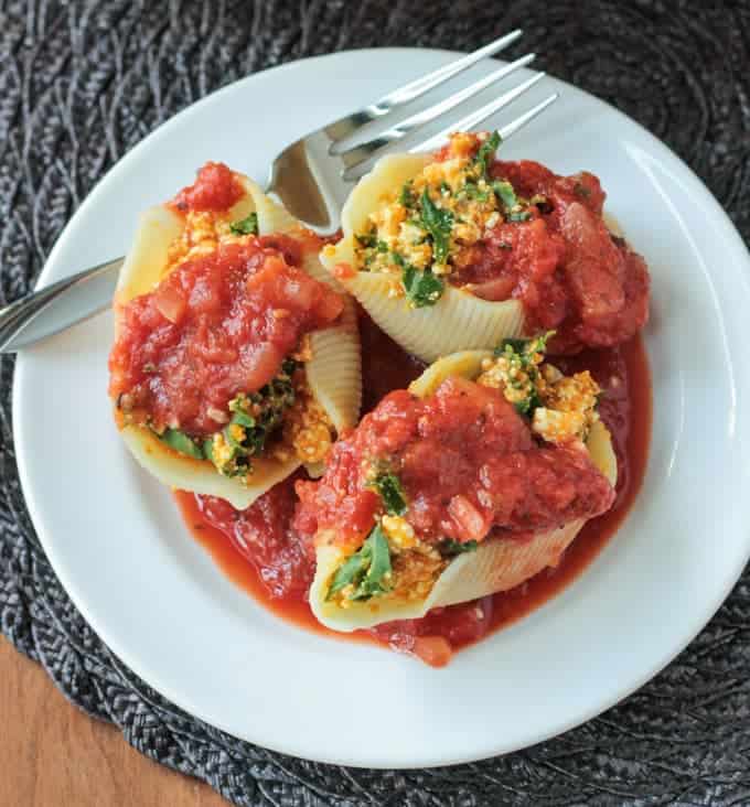 Overhead view of 3 Pumpkin & Kale Vegan Stuffed Shells on a white plate next to a silver fork.