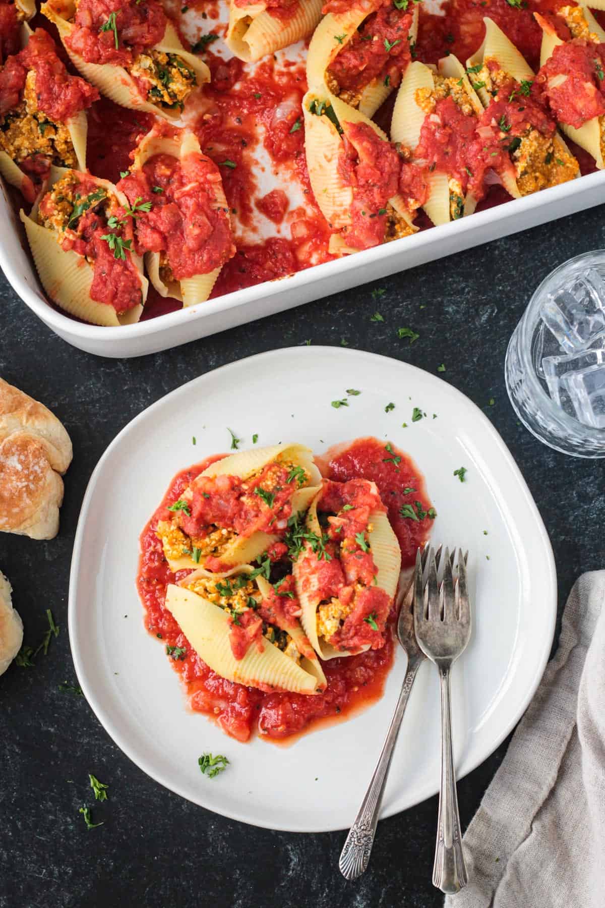 Three vegan stuffed shells on a plate with two forks.