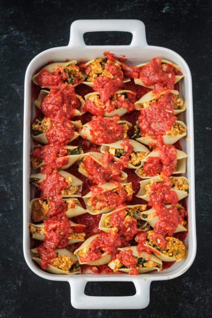 Stuffed shells covered with sauce in a baking dish.