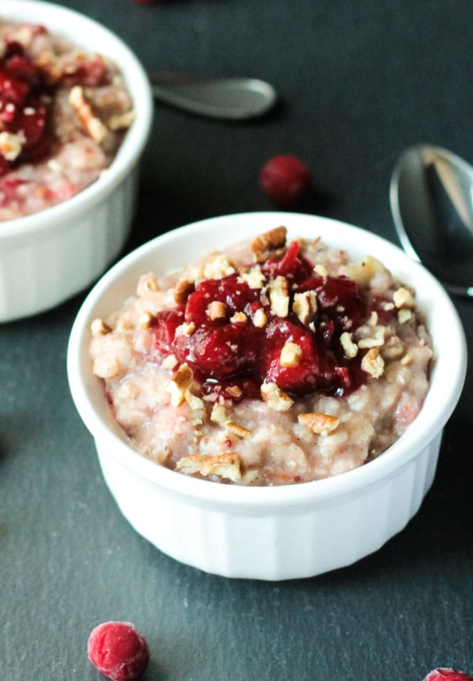 Creamy Cranberry Oatmeal in a small white bowl topped with leftover cranberry sauce and chopped pecans. 