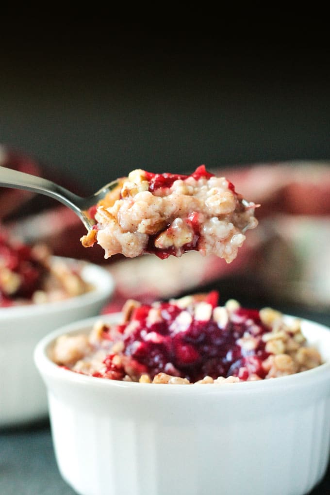 Spoonful of Creamy Cranberry Oatmeal on a spoon over a bowl of more oatmeal.