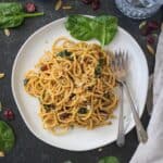 Spaghetti with spinach and cranberries on a plate with two forks.