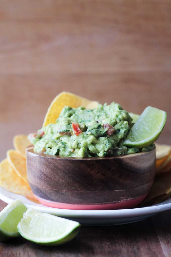 The best guacamole served with tortilla chips and garnished with lime wedges.