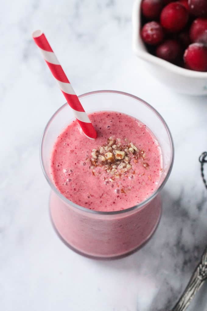 Cranberry Smoothie garnished with chopped pecans and a red/white striped straw.