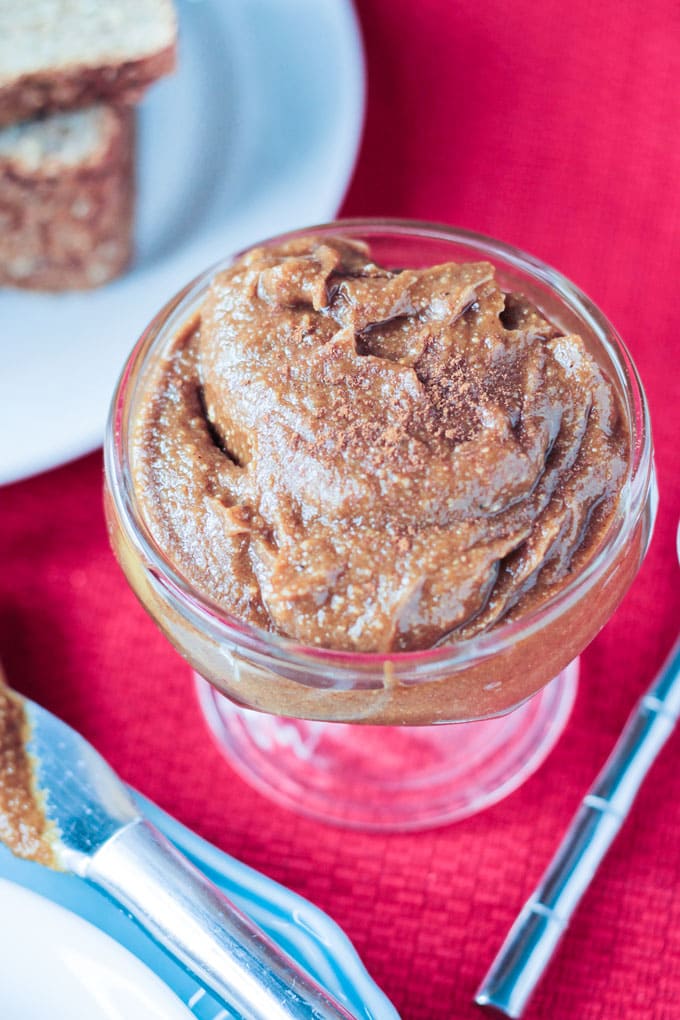 Cashew butter spread in a small glass cup sprinkled with cinnamon.