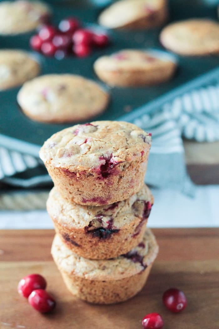 Stack of 3 baked goods in front of a muffin tin holding more muffins.