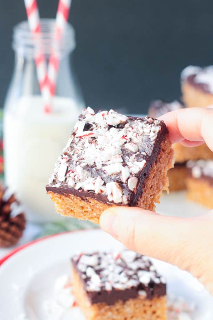 Hand holding a rice crispy bar covered in chocolate and crushed peppermint candies.