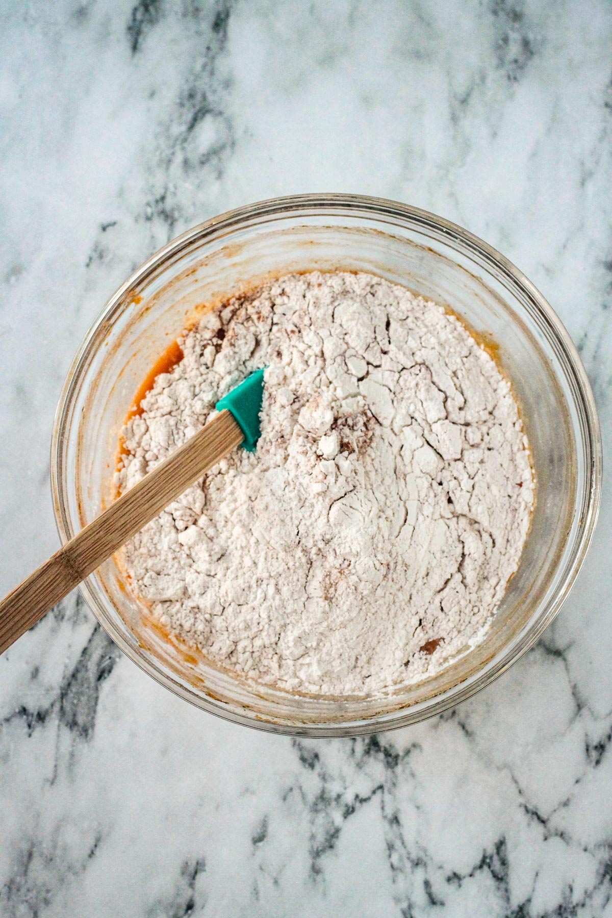 Dry ingredients on top of the wet ingredients in a mixing bowl.