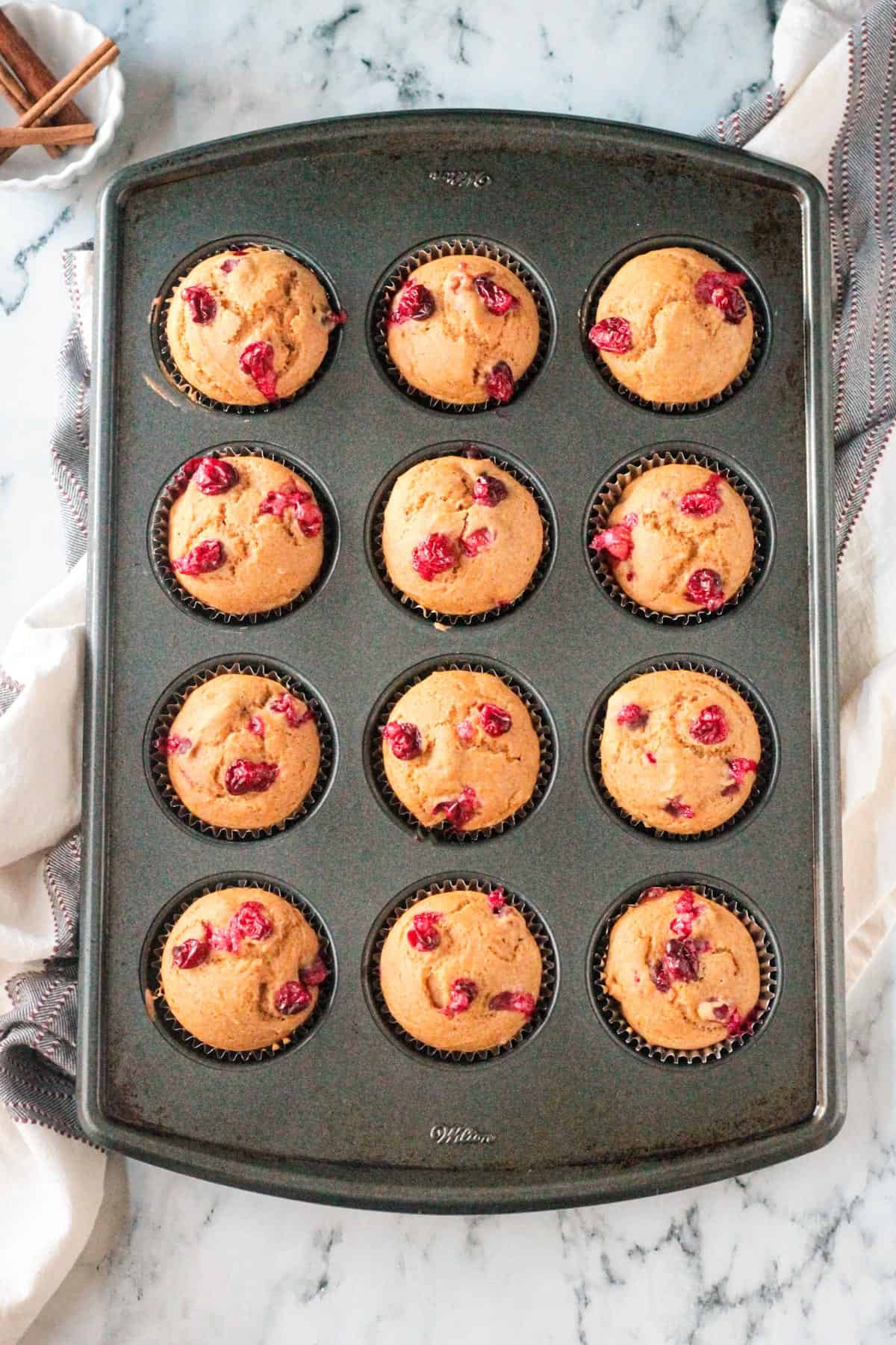 Baked cranberry muffins in a muffin tin.