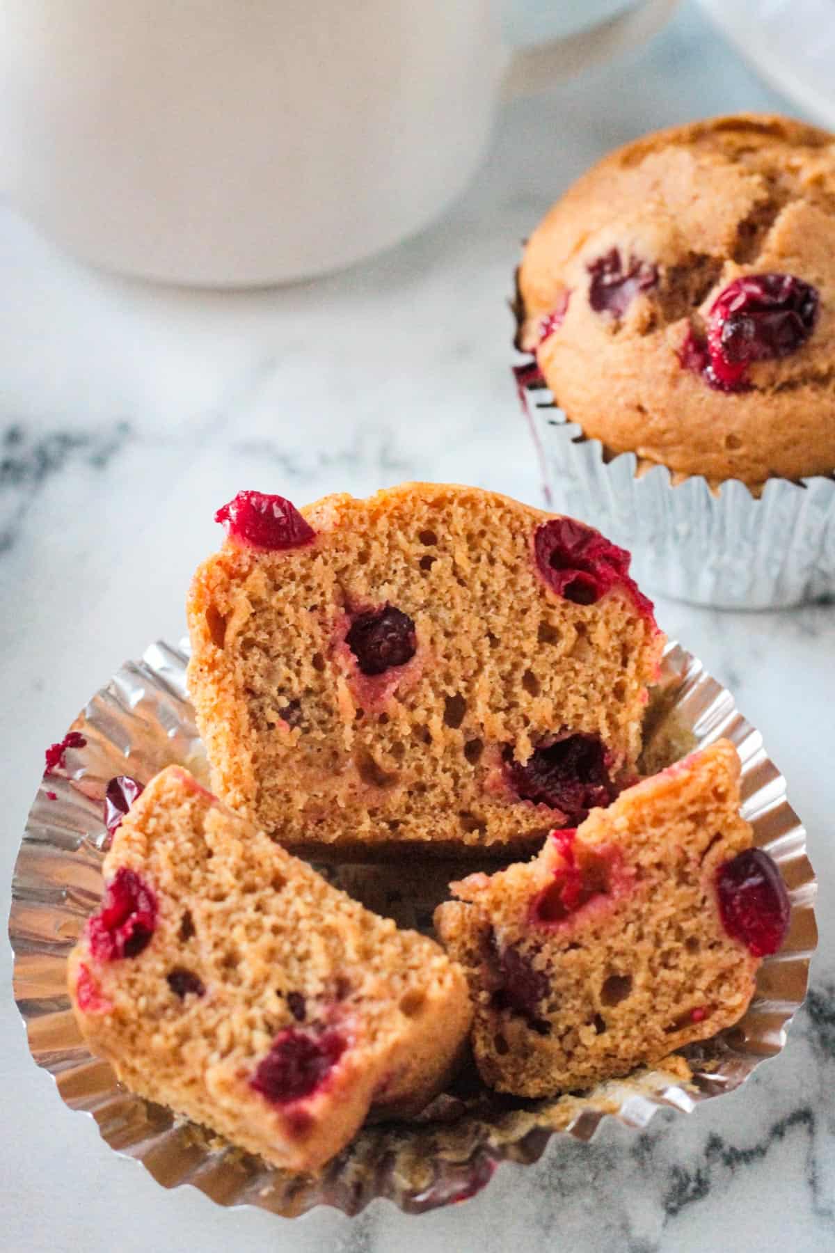 One pumpkin cranberry muffin cut into 3 pieces showing the fluffy inside.
