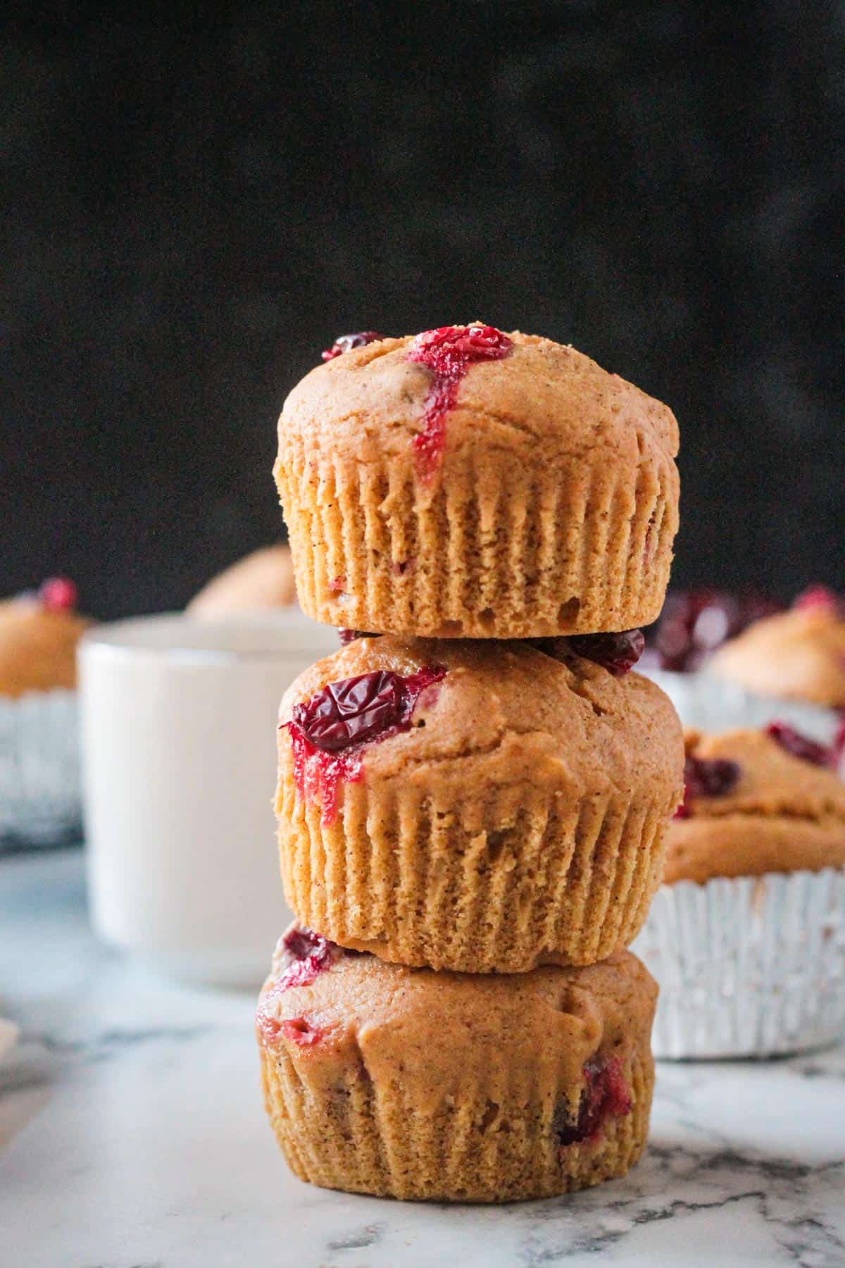 Stack of three pumpkin cranberry muffins.