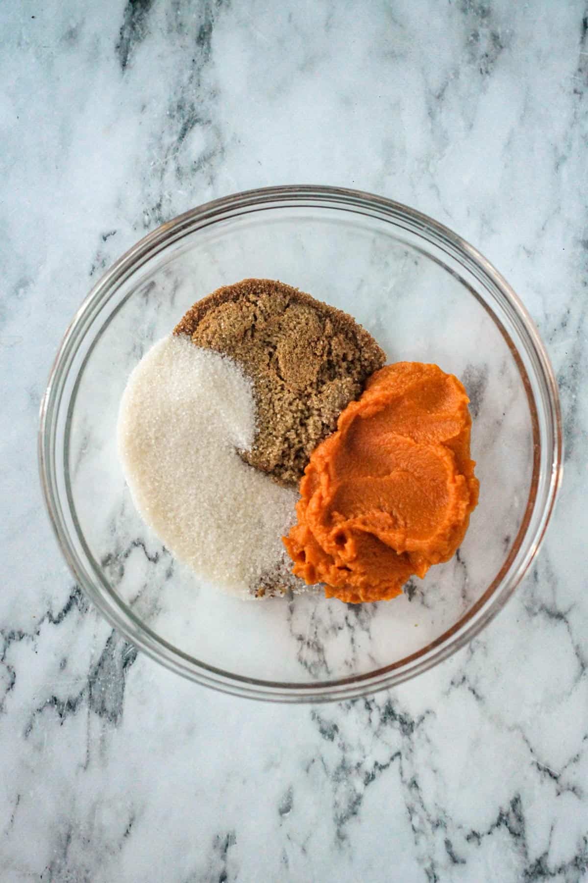 Brown sugar, white sugar, and pumpkin purée in a mixing bowl.