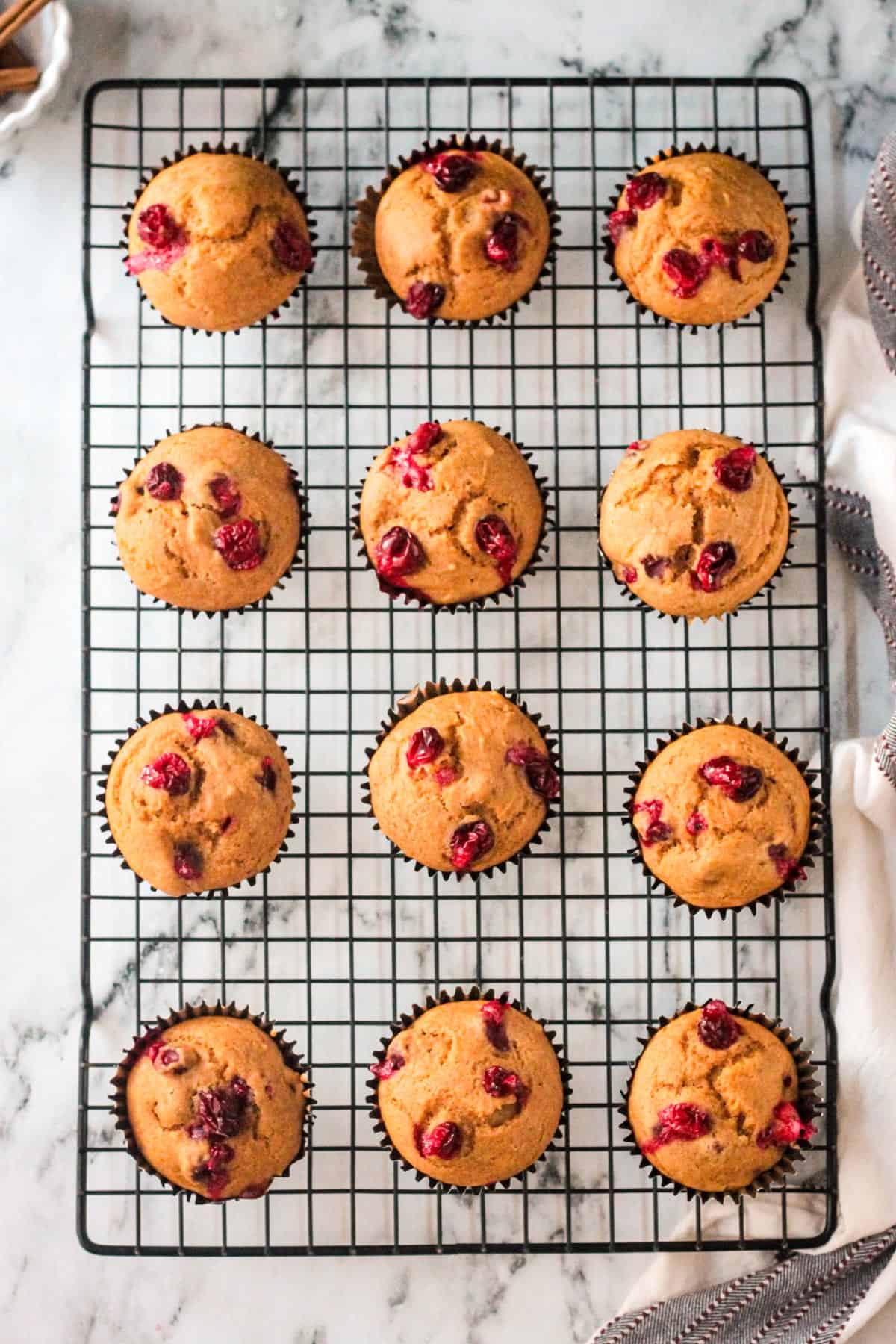 All of the baked muffins on a wire cooling rack.