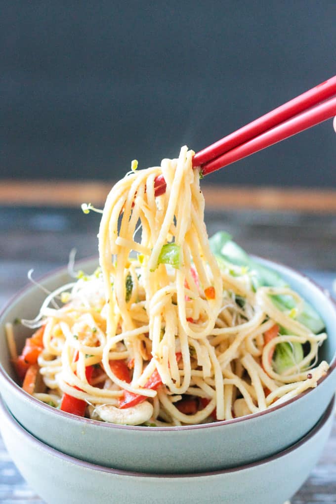 Chopsticks pulling up a bite of lo mein noodles.