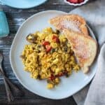 Tofu veggie scramble on a plate with two pieces of buttered toast.