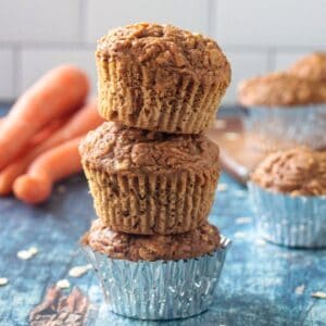 Three vegan carrot muffins stacked on top of each other.