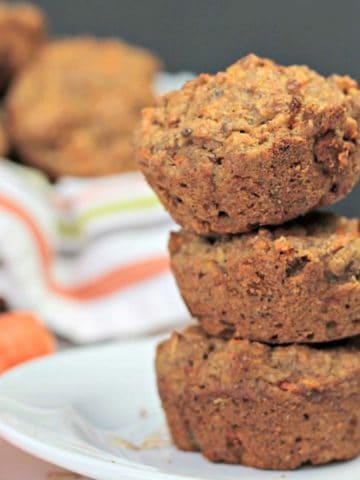 Stack of 3 vegan carrot oat muffins on a white plate.