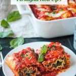 Two lasagna roll ups on a white plate garnished with fresh basil.