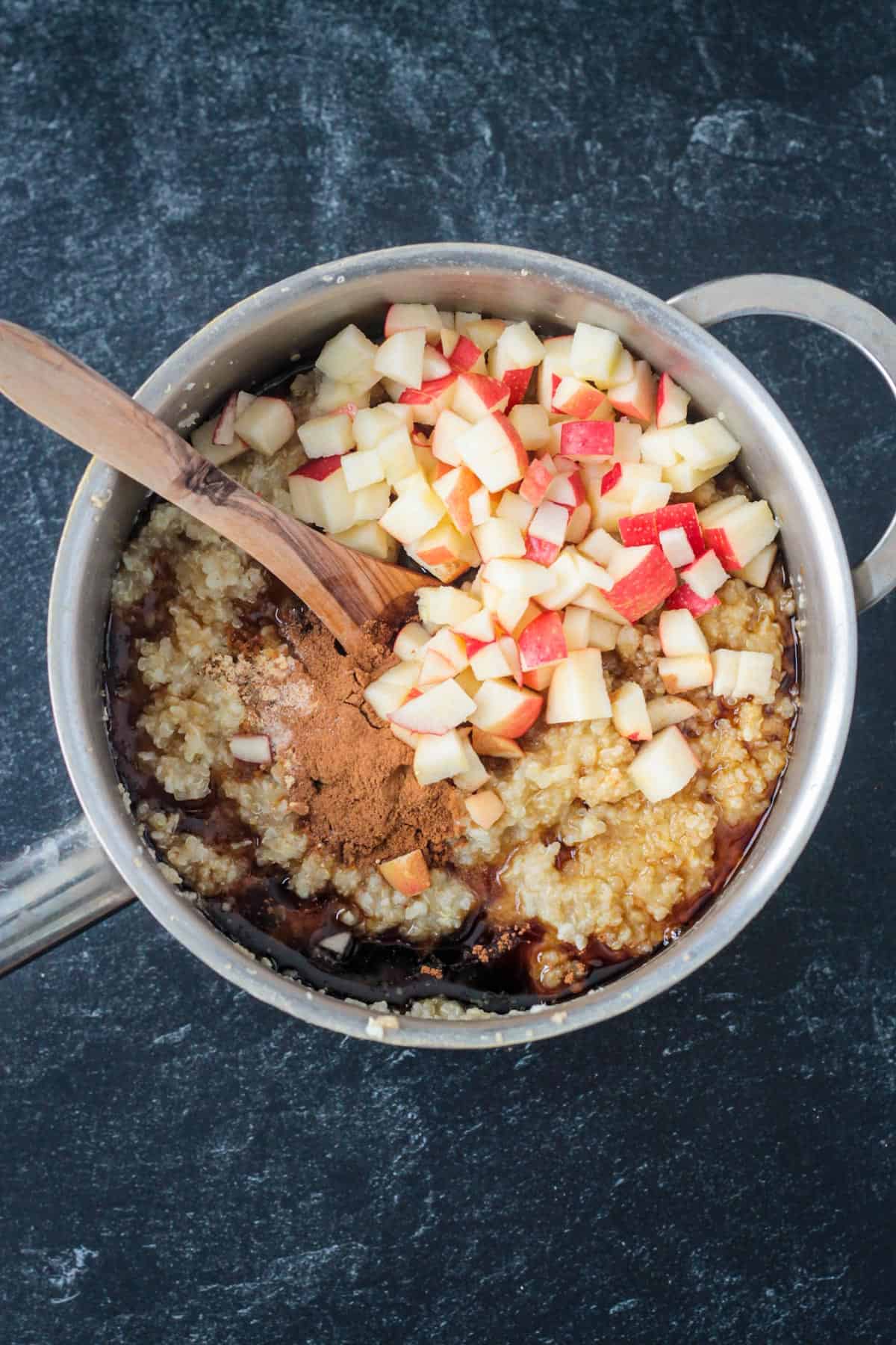 Chopped apples, spices, and maple syrup added to a pot of whole grain porridge.