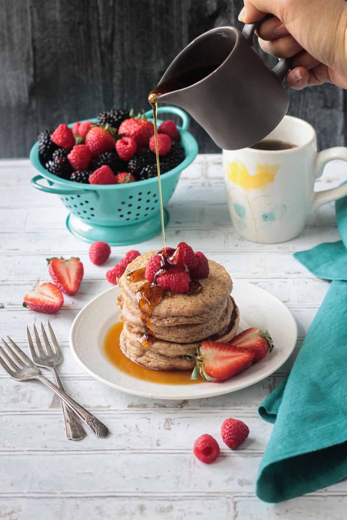 syrup being drizzled over a stack of pancakes