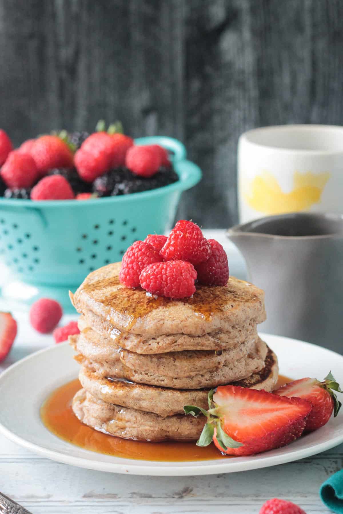 Stack of pancakes topped with fresh berries and syrup.