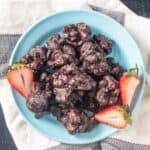 Overhead view of a plate of chocolate covered cashew clusters.