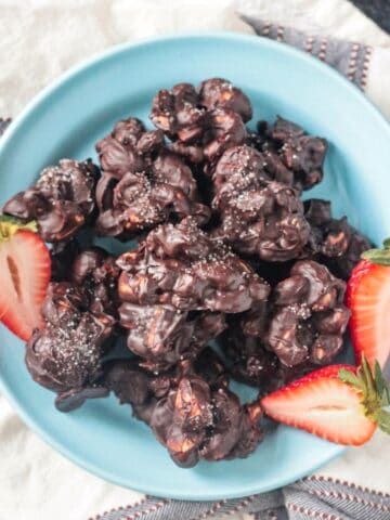 Overhead view of a plate of chocolate covered cashew clusters.