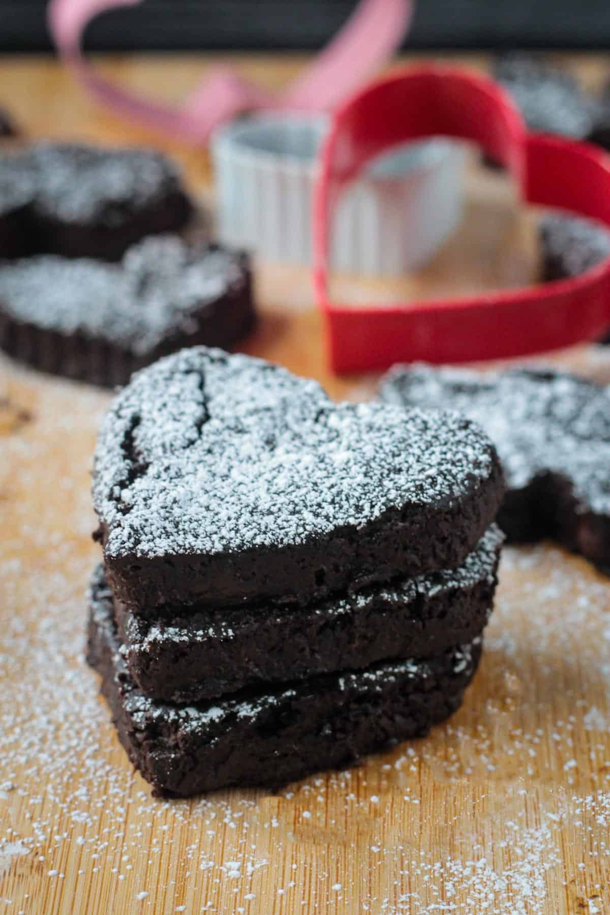 Stack of 3 vegan black bean brownies sprinkled with powdered sugar.