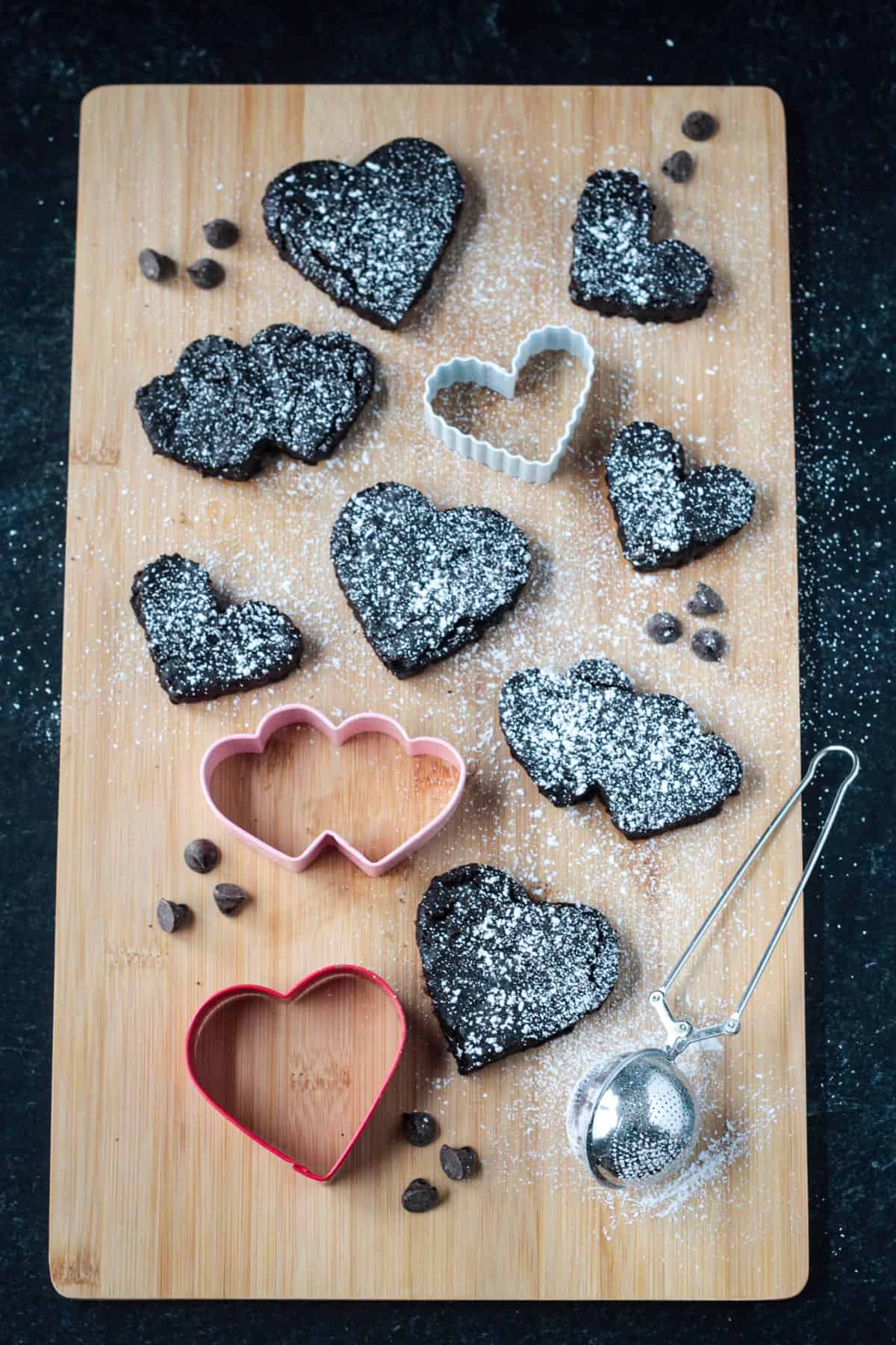 Powdered sugar sprinkled over the tops of heart shaped brownies.