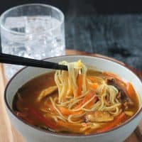 Chopsticks pulling noodles out of the bowl