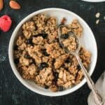 Almond granola in a white bowl with a spoon.